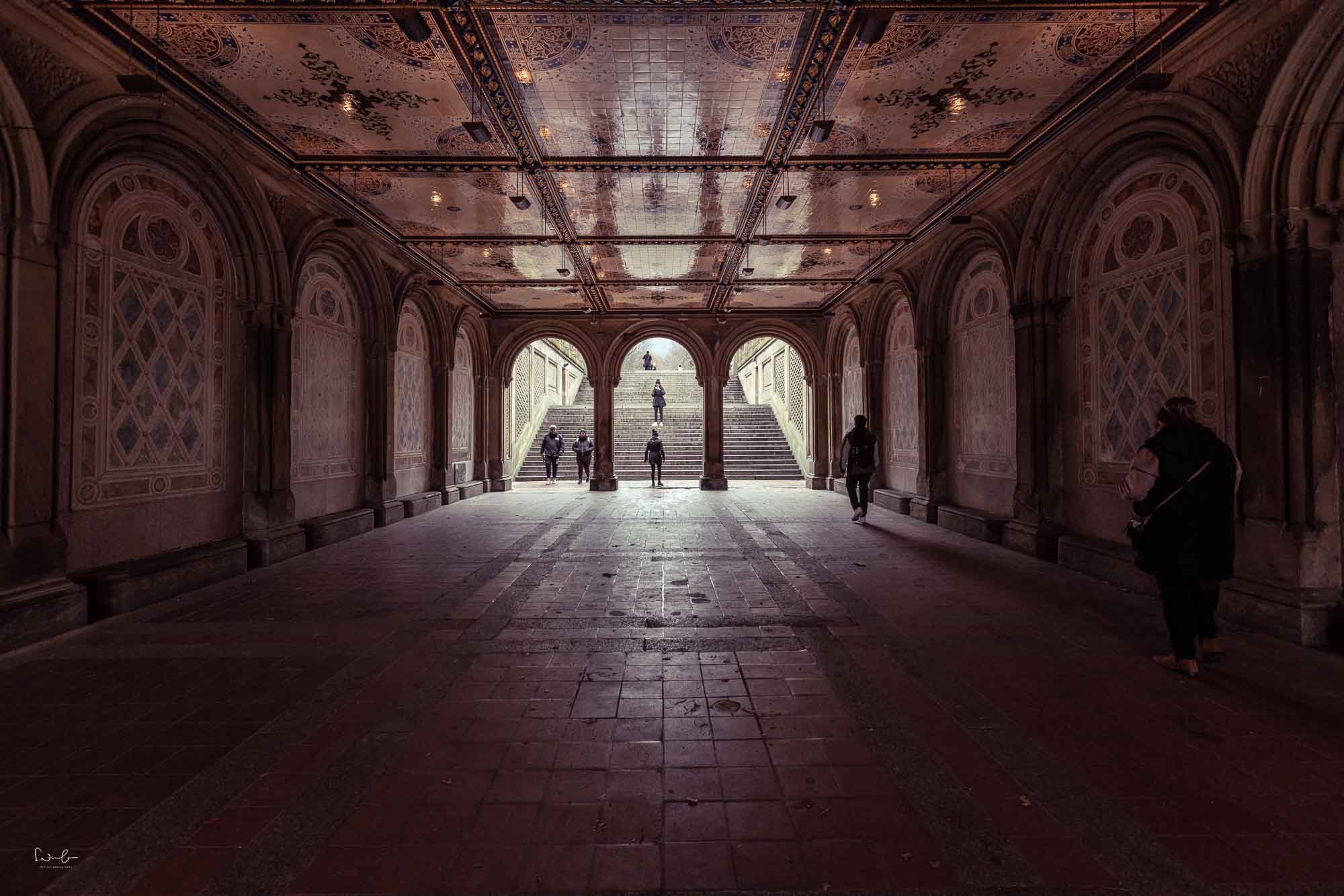 Bethesda Terrace New York Unterführung mit Menschen in normaler Perspektive und symmetrischer Architektur im Hintergrund.